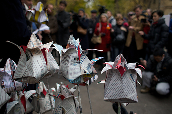 People lay flowers made of newspapers to pay respects to slain Novaya Gazeta journalist Anna Politkovskaya outside the newspaper's office in Moscow, October 7, 2014. (AP/Ivan Sekretarev)