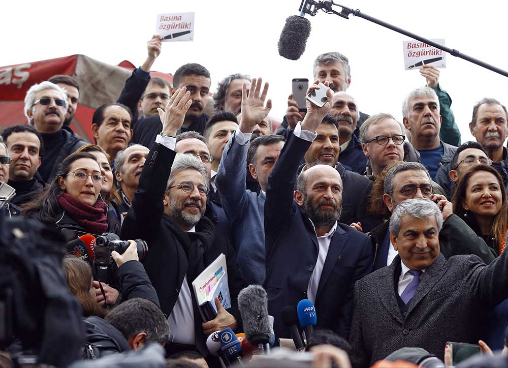 Dönemin Cumhuriyet Genel Yayın Yönetmeni Can Dündar (ortada, solda) ve Ankara Büro Şefi Erdem Gül, Mart 2016'da, İstanbul'daki bir mahkemeye gelirken destekçilerini selamlıyorlar. (Reuters/Osman Orsal)
