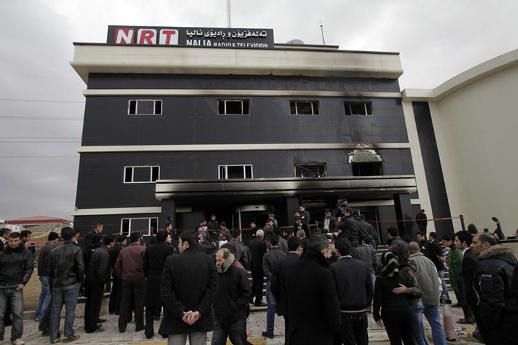 Staff and neighbors of the NRT satellite channel gather outside the station's damaged office in Sulaymaniyah, February 20, 2011. Gunmen raided and set fire to the television station in northern Iraq. (Reuters)