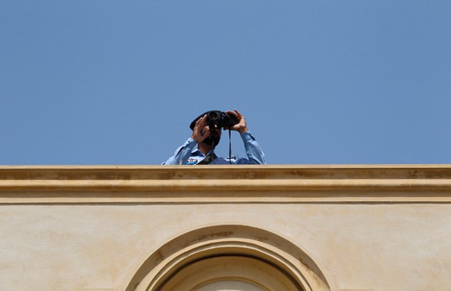 A security official looks through binoculars from the roof of the High Court in Islamabad, April 12, 2013 (Reuters/Milan Kursheed)