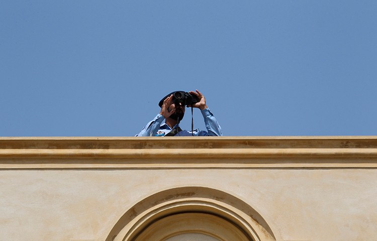 A security official looks through binoculars from the roof of the High Court in Islamabad, April 12, 2013 (Reuters/Milan Kursheed)