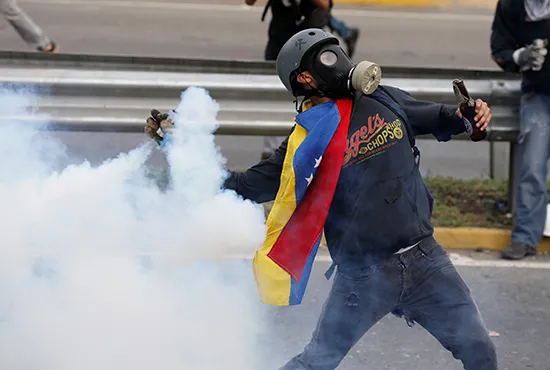Un manifestante lanza una bomba lacrimógena a la policía en Caracas, el 2 de mayo de 2017. (Reuters/Carlos Garcia Rawlins)