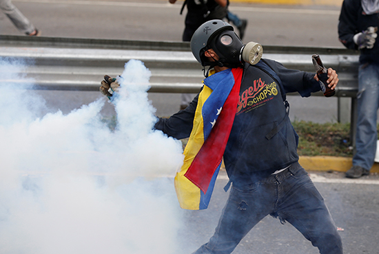 Um manifestante lança uma lata de gás lacrimogêneo de volta à polícia em Caracas, 2 de maio de 2017. (Reuters / Carlos Garcia Rawlins)