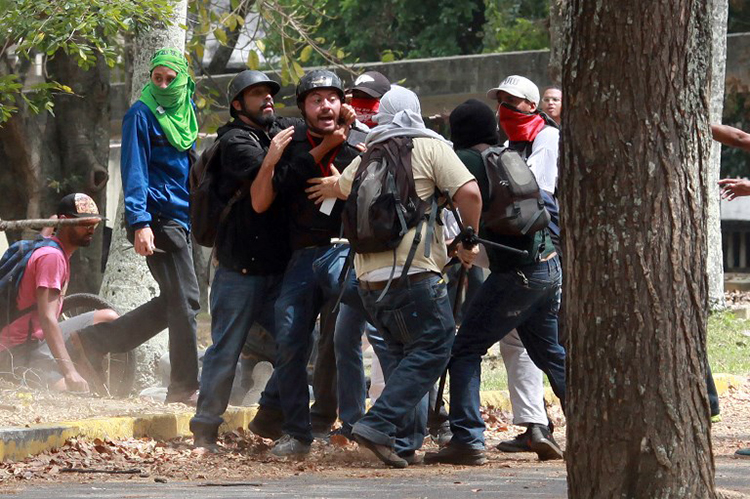 Members of a "colectivo" pro-government group attack Leonardo Rodriguez (center), a photographer for the pro-opposition newspaper El Nacional, as he covered a student protest at Venezuelan Central University (UCV) in Caracas, April 3, 2014. (AFP/Federico Parra)