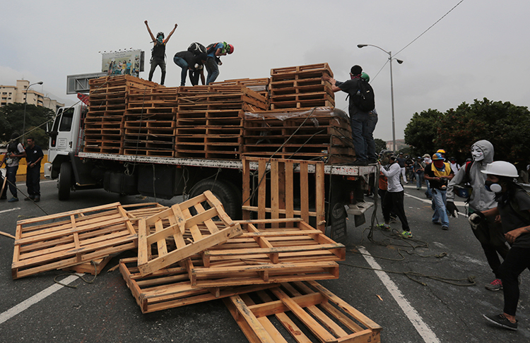 Protesters unload pallets from a truck they forced to stop on a highway in Caracas, May 22, 2017. (AP/Fernando Llano)