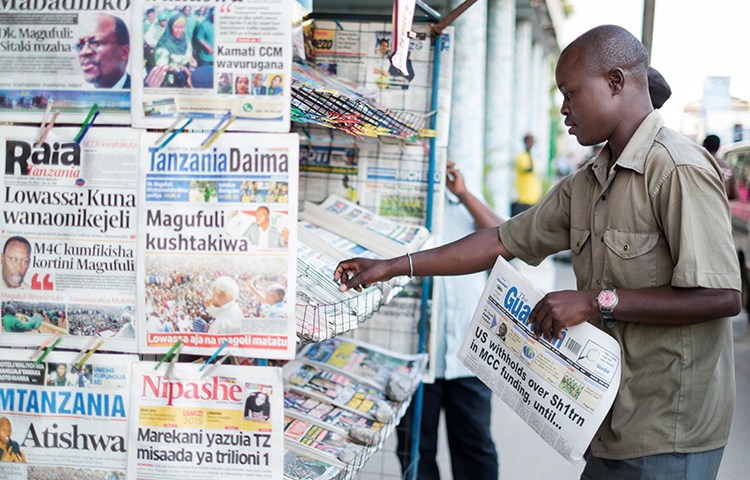 A newspaper vendor straightens papers at his stand in Tanzania in September 2015. The country's Information Minister has imposed a 24-month ban on the weekly, Mawio. (AFP/Daniel Hayduk)