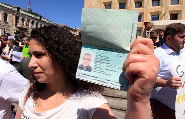 Leyla Mustafayeva holds her husband's passport at a May 29 rally in Tbilisi to protest the detention of Afgan Mukhtarli, who was abducted and forcibly taken to Azerbaijan. (AP/Shakh Aivazov)