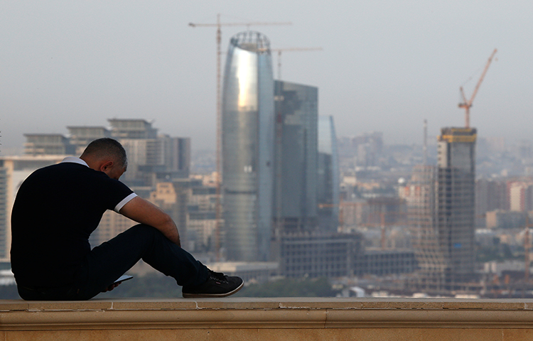 A man sits on a parapet in Baku in June 2016. A court in the Azerbaijani capital sentenced a journalist to seven years in jail. (Reuters/Maxim Shemetov)