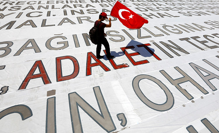 A man with a Turkish flag walks over the word "Adelet," or "Justice," at a July 9, 2017, rally in Istanbul organized by the country's largest opposition party to protest the arrest of lawmaker and former editor Enis Berberoğlu. (Reuters/Umit Bektas)