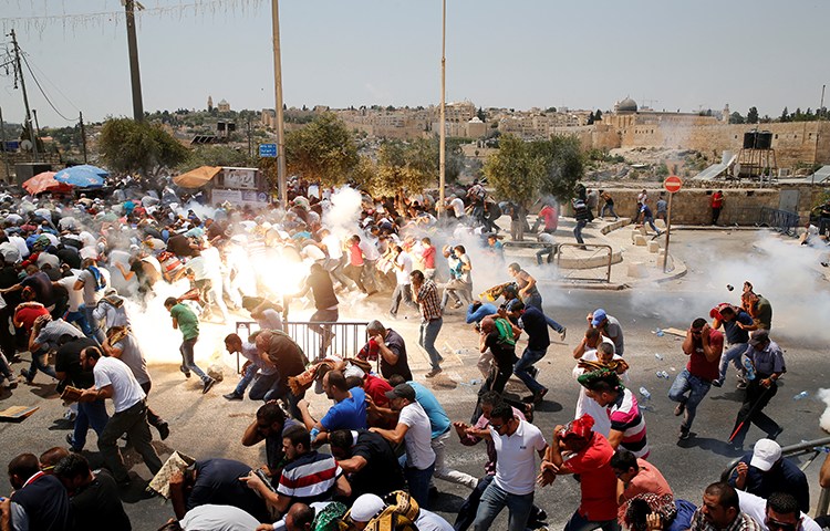 Palestinians run from tear gas and sound grenades at a July 21, 2017, protest outside Jerusalem's old city. (Reuters/Ammar Awad)