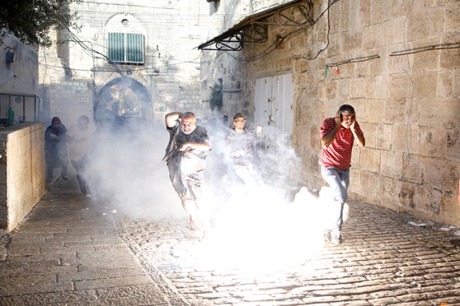 Palestinians run from tear gas and stun grenades in the old city of Jerusalem, July 27, 2017. (Reuters/Amir Cohen)