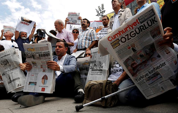 Journalists and press freedom advocates read Cumhuriyet newspaper at a protest demanding the release of 17 employees and directors of the newspaper outside their trial in Istanbul, July 28, 2017. (Reuters/Murad Sezer)