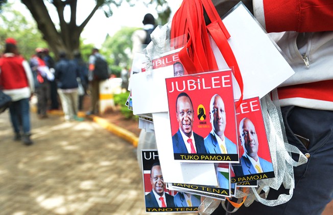 A vendor sells badges of Kenya's President Uhuru Kenyatta, left, and his deputy William Ruto in May. Kenya is seeking to restrict commentary on social media ahead of the August elections. (AFP/Simon Maina)