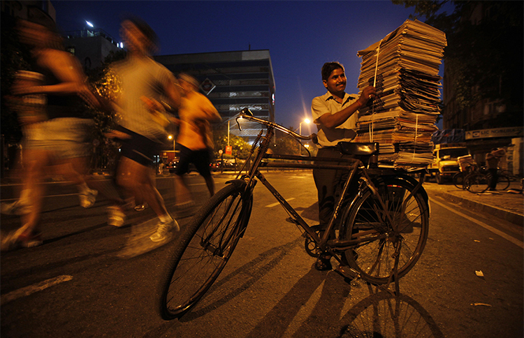 A newspaper vendor stacks newspapers on his bicycle in Mumbai. Indian journalists say companies are using the legal notices as an attempt to silence critical reporting. (AP/Rajesh Kumar Singh)
