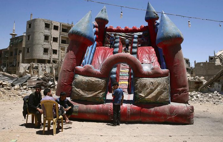 Children play in an inflatable castle in the rebel-held city of Douma, Syria, June 26, 2017. (Reuters/Bassem Khabieh)