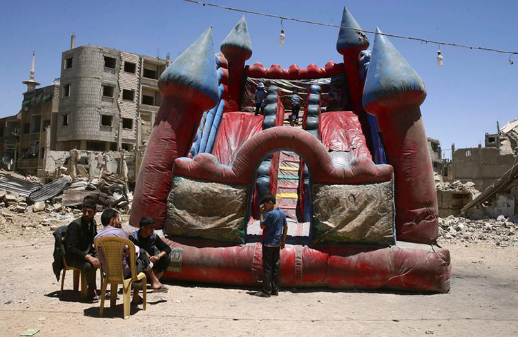 Children play in an inflatable castle in the rebel-held city of Douma, Syria, June 26, 2017. (Reuters/Bassem Khabieh)
