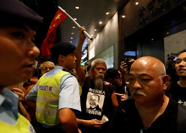 A protester carrying a defaced Chinese national flag is blocked by a police officer during a march to mourn the death of Nobel laureate Liu Xiaobo, in Hong Kong, July 15, 2017. A court in Dali, China, on August 3, 2017, sentenced journalist Lu Yuyu to four years in prison for his work documenting protests on social media. (Reuters/Bobby Yip)