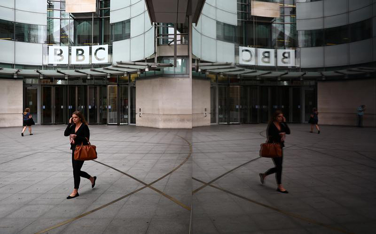A woman is reflected as she passes the BBC's broadcasting house in London, July 19, 2017. (Reuters/Neil Hall)