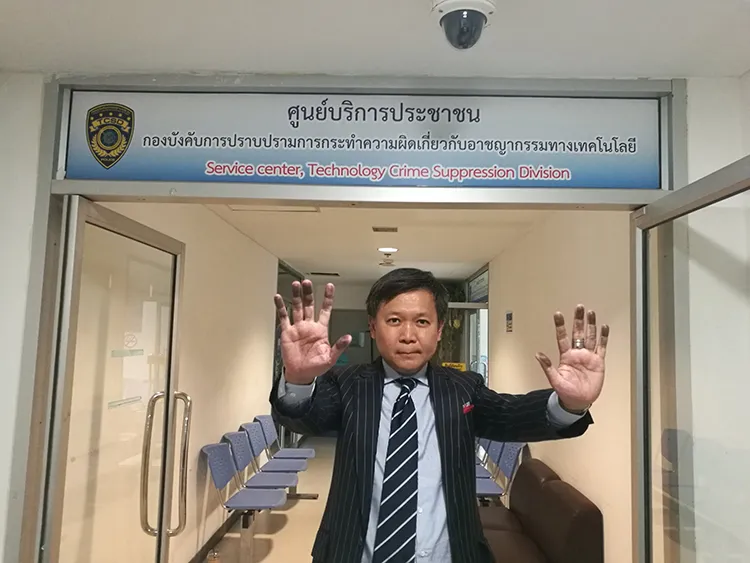 Thai columnist Pravit Rojanaphruk raises his hands, stained by ink from being fingerprinted, at the Royal Thai Police's Technology Crime Suppression Division in Bangkok, August 8, 2017. (Pravit Rojanaphruk)