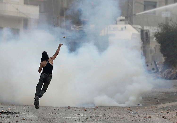A Palestinian man hurls stones at Israeli soldiers in the West Bank village of Deir Abu Mashal, near Ramallah, August 10, 2017. Israeli and Palestinian security forces have increased repression of the media as political tensions have increased in recent weeks. (Reuters/Mohamad Torokman)
