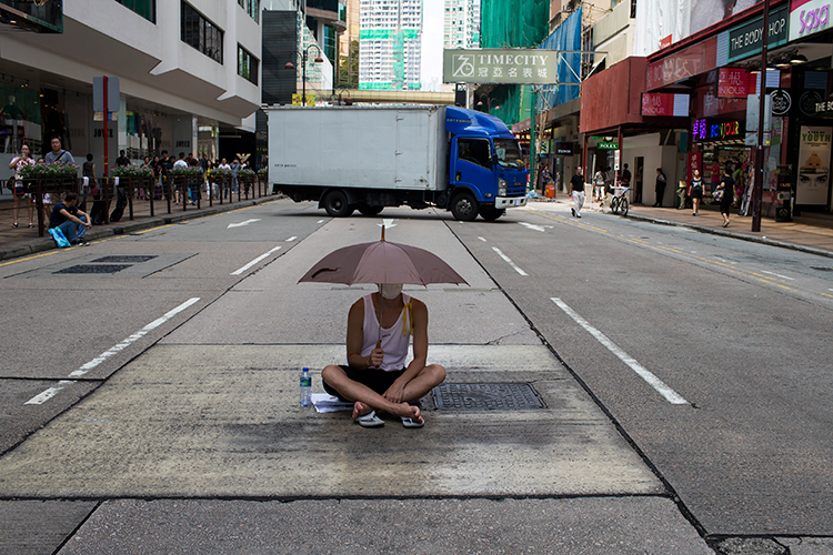 A protester sits under an umbrella as he attends an October 1, 2014 demonstration in Hong Kong. Reporter Mak Ying-sheung faces contempt of court charges after she was arrested while reporting on a November 2014 protest. (Reuters/Tyrone Siu)