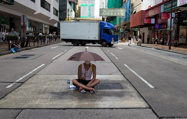 A protester sits under an umbrella as he attends an October 1, 2014 demonstration in Hong Kong. Reporter Mak Ying-sheung faces contempt of court charges after she was arrested while reporting on a November 2014 protest. (Reuters/Tyrone Siu)