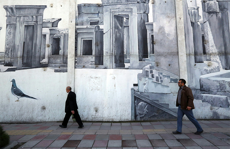 Iranians walk past street art in the southwestern district of Tehran in January 2016. Security agents arrested two journalists in the city in August (AFP/Atta Kenare)