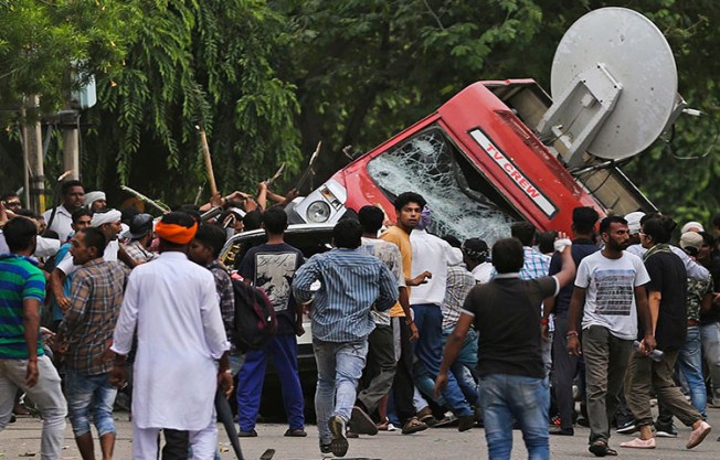 Sect members overturn a broadcasting van on the streets of Panchkula, India on August 25, 2017. Deadly riots have broken out in a north Indian town after a court convicted their guru of raping two of his followers.(AP Photo/Altaf Qadri)