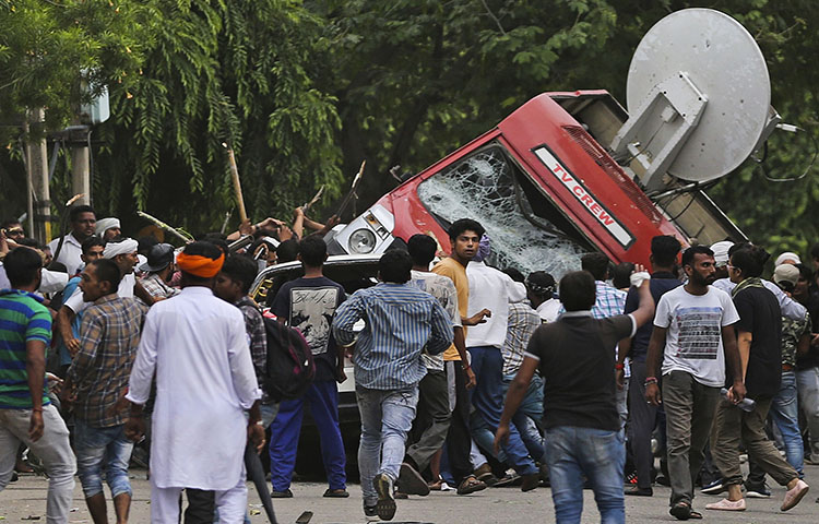 Sect members overturn a broadcasting van on the streets of Panchkula, India on August 25, 2017. Deadly riots have broken out in a north Indian town after a court convicted their guru of raping two of his followers.(AP Photo/Altaf Qadri)
