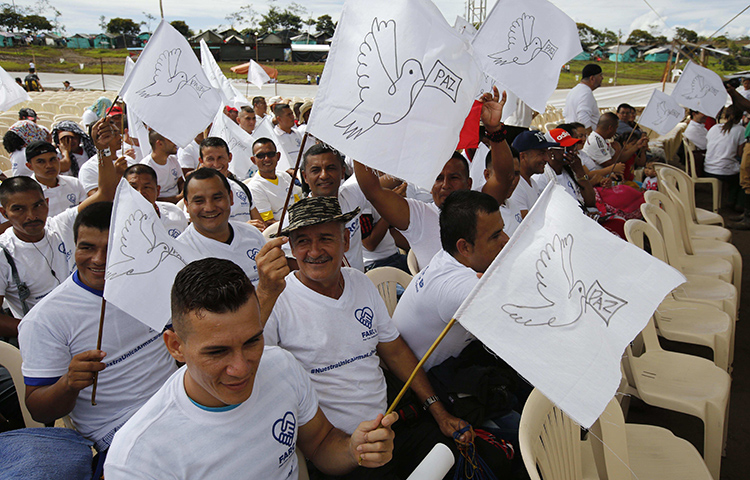 Guerrillas de las Fuerzas Armada Revolucionarias de Colombia (FARC), alzan banderas de paz blancas durante un acto para conmemora el fin de su proceso de desarmamiento en Buenavista, Colombia, el 27 de junio de 2017. (AP/Fernando Vergara)