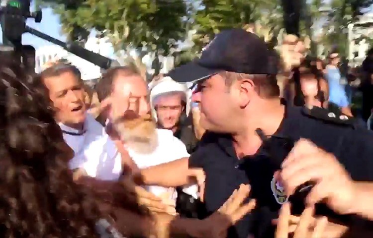 A screen shot of a Dihaber video shows a police officer scuffling with journalists at an August 6 opposition party protest in Istanbul.