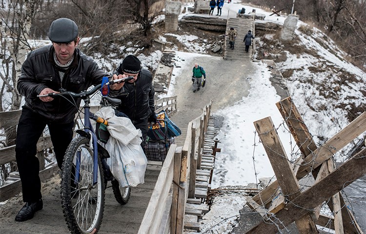 Residents cross a bridge damaged during fighting between Ukrainian government forces and Pro-Russian rebels near Luhanska, eastern Ukraine, in January 2016. Separatists are holding a blogger over his critical posts. (AP/Evgeniy Maloletka)