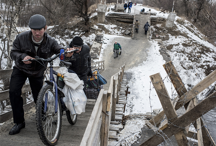 Residents cross a bridge damaged during fighting between Ukrainian government forces and Pro-Russian rebels near Luhanska, eastern Ukraine, in January 2016. Separatists are holding a blogger over his critical posts. (AP/Evgeniy Maloletka)