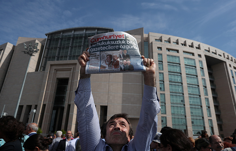 A press freedom activist holds a copy of the opposition newspaper Cumhuriyet during a demonstration in solidarity with the jailed members of the opposition newspaper outside a courthouse, in Istanbul on September 25. (Reuters/Osman Orsal)