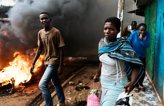 Residents pass a burning barricade in Kibera, Nairobi, on October 25, the day before presidential re-elections are held. Journalists covering the vote should take safety precautions. (AFP/Marco Longari)