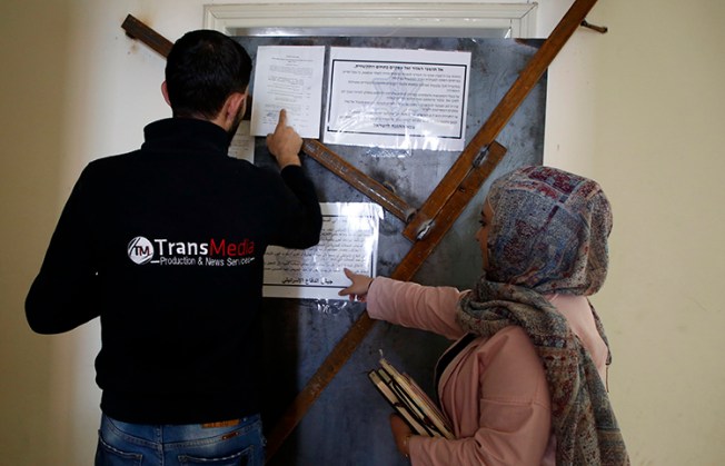 Employees of TransMedia look at a military order attached to their office doors in Hebron on October 18, 2017. Israeli forces raided several media companies for alleged incitement. (AFP/Hazem Bader)