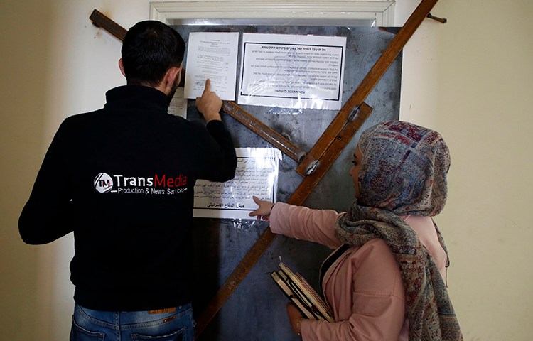 Employees of TransMedia look at a military order attached to their office doors in Hebron on October 18, 2017. Israeli forces raided several media companies for alleged incitement. (AFP/Hazem Bader)