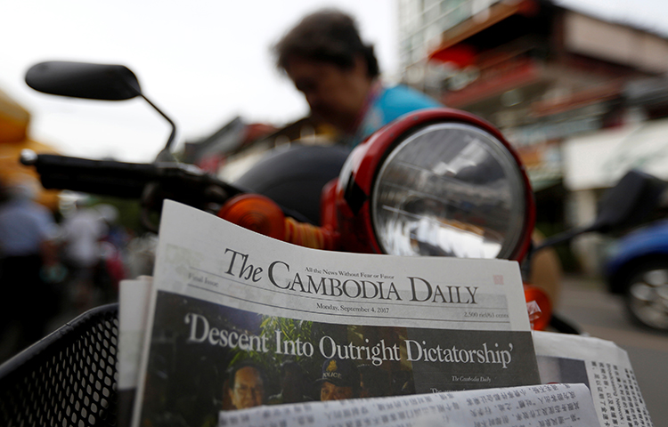 A woman buys the final issue of the Cambodia Daily newspaper at a store in Phnom Penh, Cambodia, September 4, 2017. (Reuters/Samrang Pring)