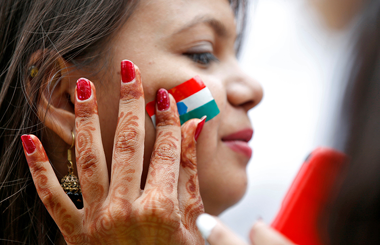 An Indian flag is painted on a woman's face during rehearsals for India's Independence Day celebrations in Ahmedabad. A court in the city issued an injunction against the news website The Wire. (Reuters/Amit Dave)