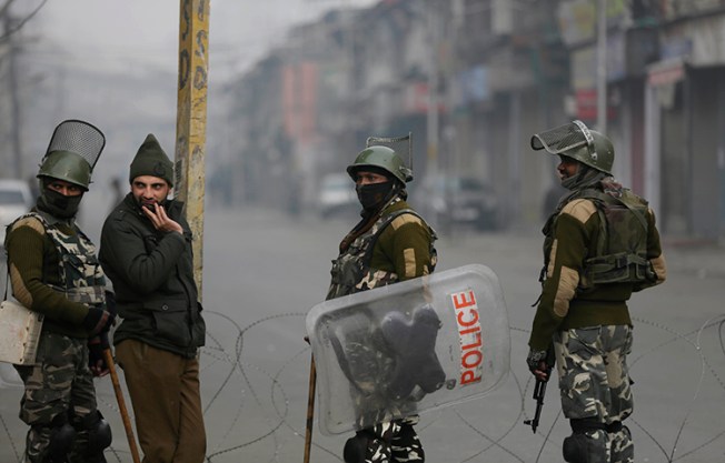 Indian paramilitary soldiers and a policeman, second from left, guard a checkpoint during a strike to mark International Human Rights Day in Srinagar, India, on December 10, 2017. State police arrested french filmmaker Comiti Paul Edwards on December 9, in Srinagar while he was shooting a documentary on people injured by pellet guns. (AP/Mukhtar Khan)