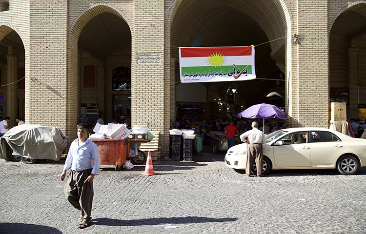 In this Thursday, Aug. 24, 2017 photo, a man walks past a campaign poster printed on a Kurdish flag urging people to vote yes in the poll on independence from Iraq, Irbil, Iraq. The Committee to Protect Journalists today condemned theclosure of an independent television broadcaster by the Kurdish authorities in northernIraq, and attacks on journalists covering anti-austerity protests held yesterday in thesame region.(AP/Balint Szlanko)
