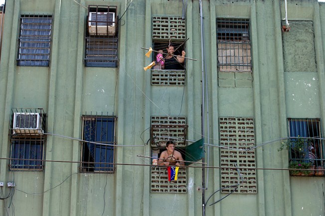Residents in a Valencia apartment block watch a rally on the street below in March 2014. Several of the city's critical newspapers have been forced out of circulation amid Venezuela's economic crisis and newsprint shortage. (AP/Fernando Llano)