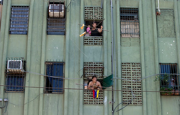 Residents in a Valencia apartment block watch a rally on the street below in March 2014. Several of the city's critical newspapers have been forced out of circulation amid Venezuela's economic crisis and newsprint shortage. (AP/Fernando Llano)