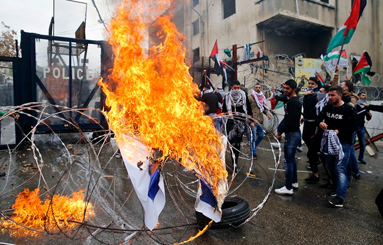 Protesters burn an Israeli flag in front of the U.S. Embassy in Lebanon, during a demonstration in Aukar, east of Beirut, on December 10. Rallies are being held in several countries after President Donald Trump said he will recognize Jerusalem as Israel's capital. (AP/Bilal Hussein)