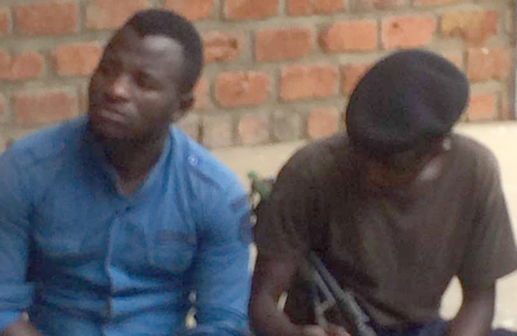 DRC journalist Benjamin Mutiya, left, pictured under police guard on December 18, is detained on defamation accusations. (Fortunat Maronga/CJDH)