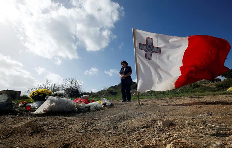 Tributes and a flag are left at the spot where investigative journalist Daphne Caruana Galizia was killed in a bombing in October. Police in Malta arrested 10 suspects in the case on December 4. (Reuters/Darrin Zammit Lupi)