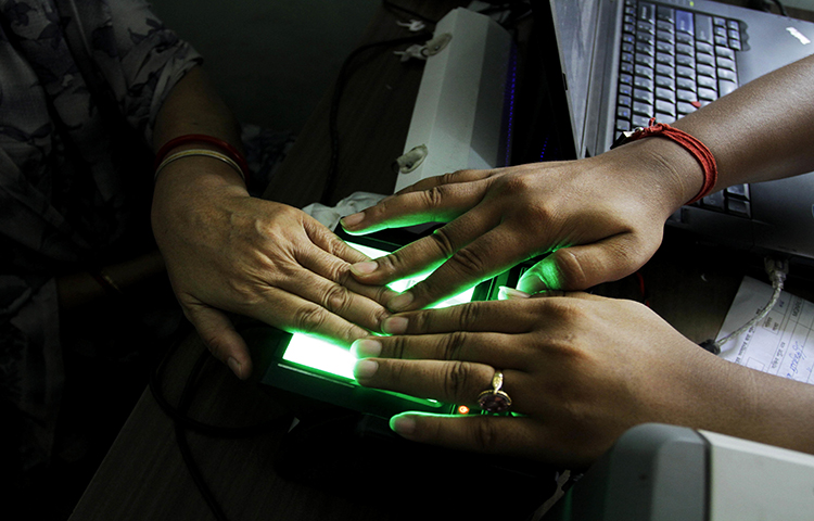 In this May 16, 2012 file photo, an operator helps an elderly woman scan her fingerprints as she enrolls for Aadhar, India's unique identification project in Kolkata, India. The country's leading English-language daily, The Tribune, published an article exposing a possible vulnerability in the system. (AP/Bikas Das)