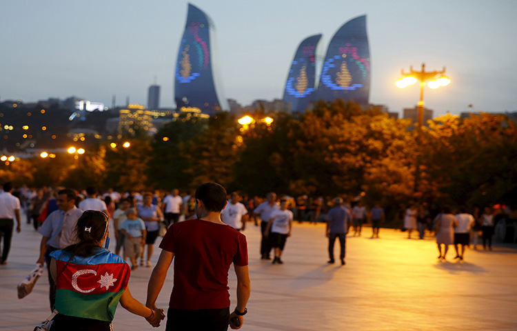 A girl, draped in Azerbaijan's national flag, walks with a boy on a street in downtown Baku, Azerbaijan on June 18, 2015. (Reuters/Stoyan Nenov)