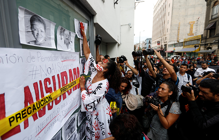 Um ativista coloca um painel de fotos de jornalistas mortos no México durante uma manifestação contra o assassinato de jornalistas no México, fora do prédio da Promotoria Especial de Atenção aos Crimes contra a Liberdade de Expressão (FEADLE, sigla em espanhol) na Cidade do México, México, em 15 de junho de 2017. (Reuters/Edgard Garrido)