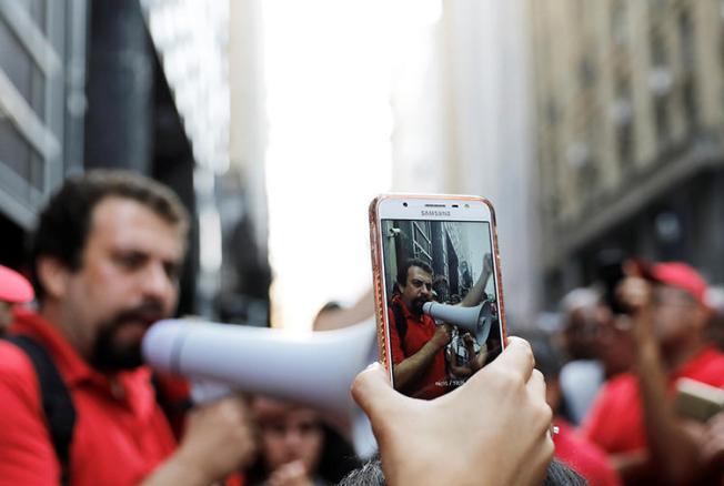 A cell phone is used to film a homelessness protest in Sao Paulo in December 2017. Ahead of October elections, police are tasked with combating the spread of fake news. (Reuters/Nacho Doce)